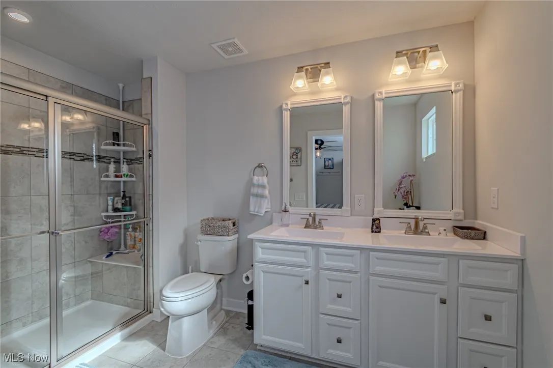 Full bathroom featuring a sink, toilet, and a stall shower