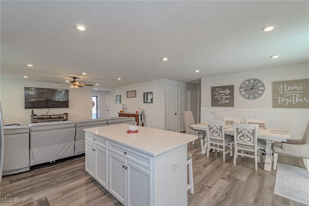 Kitchen with white cabinets, a center island, a ceiling fan, recessed lighting, and light wood finished floors