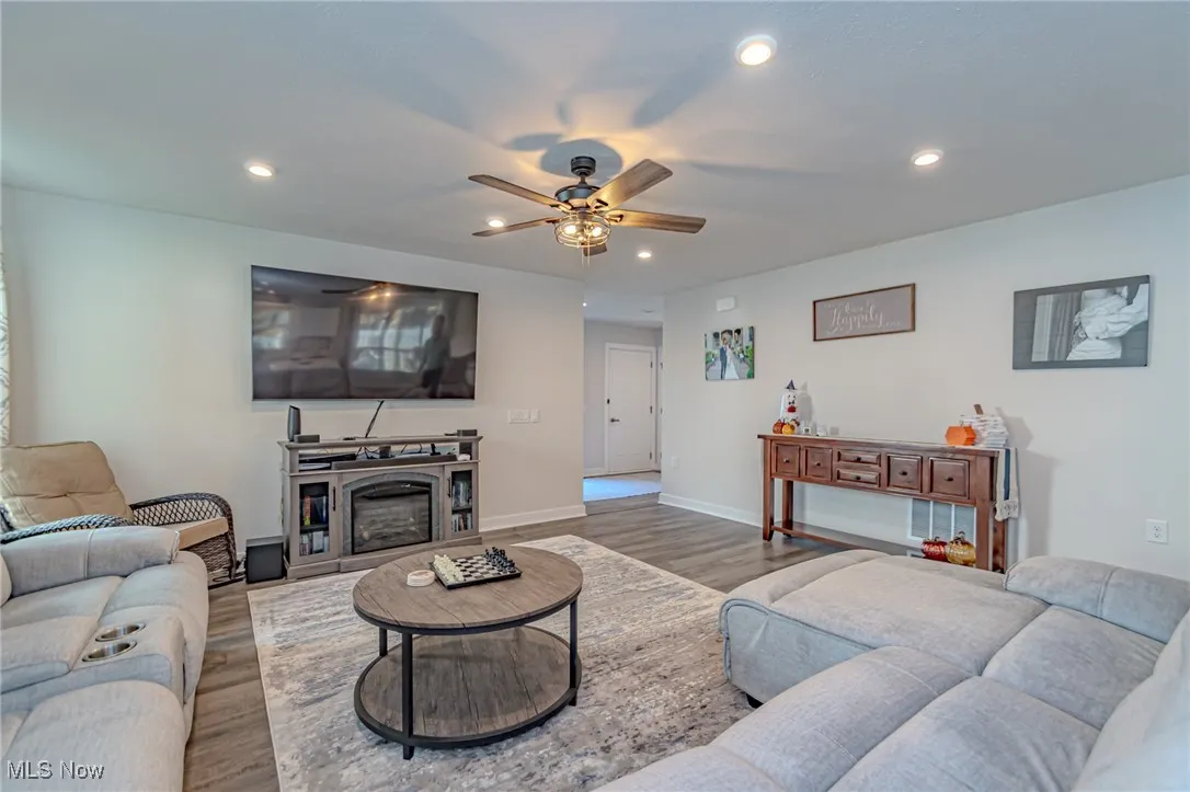 Living room with wood finished floors, ceiling fan, baseboards, and recessed lighting