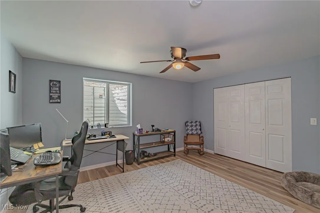 Office area with light wood-style flooring, ceiling fan, and baseboards