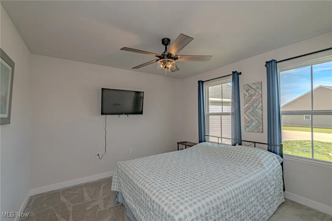 Bedroom featuring light carpet, baseboards, and a ceiling fan