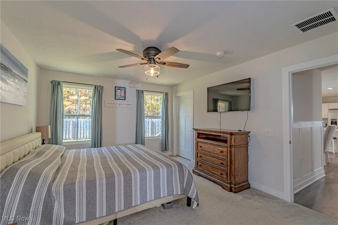 Carpeted bedroom with ceiling fan, baseboards, and visible vents