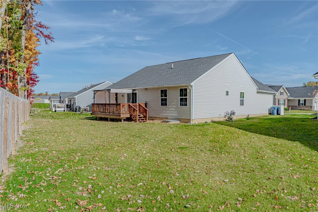 Back of property with cooling unit, a wooden deck, fence, and a lawn