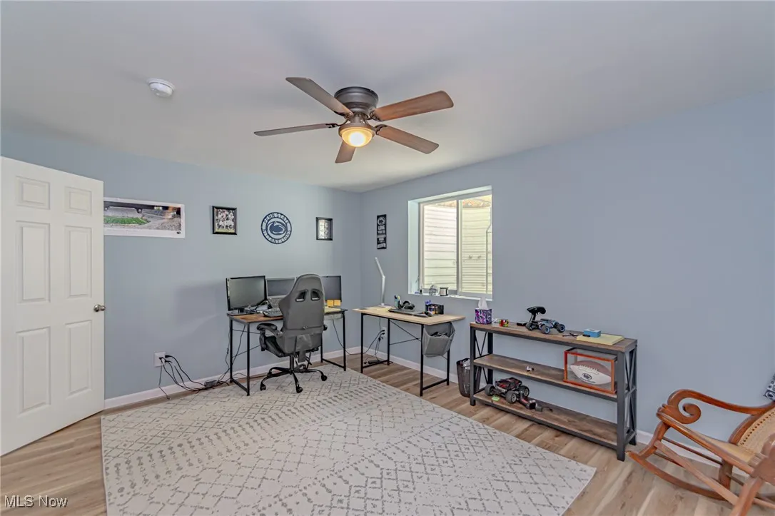 Home office featuring ceiling fan, light wood finished floors, and baseboards