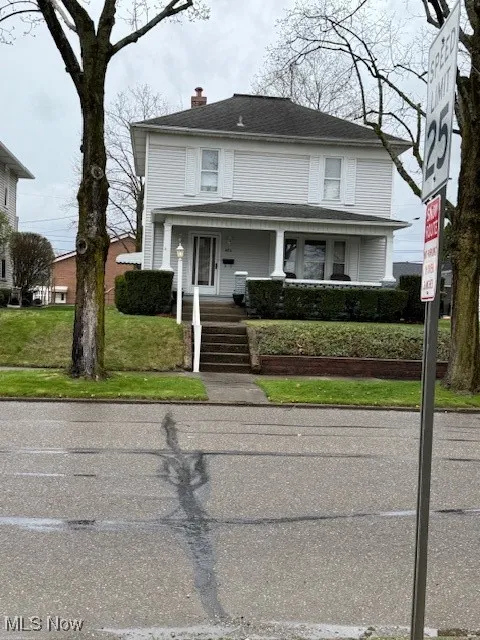 American foursquare style home with a front yard, covered porch, and a chimney