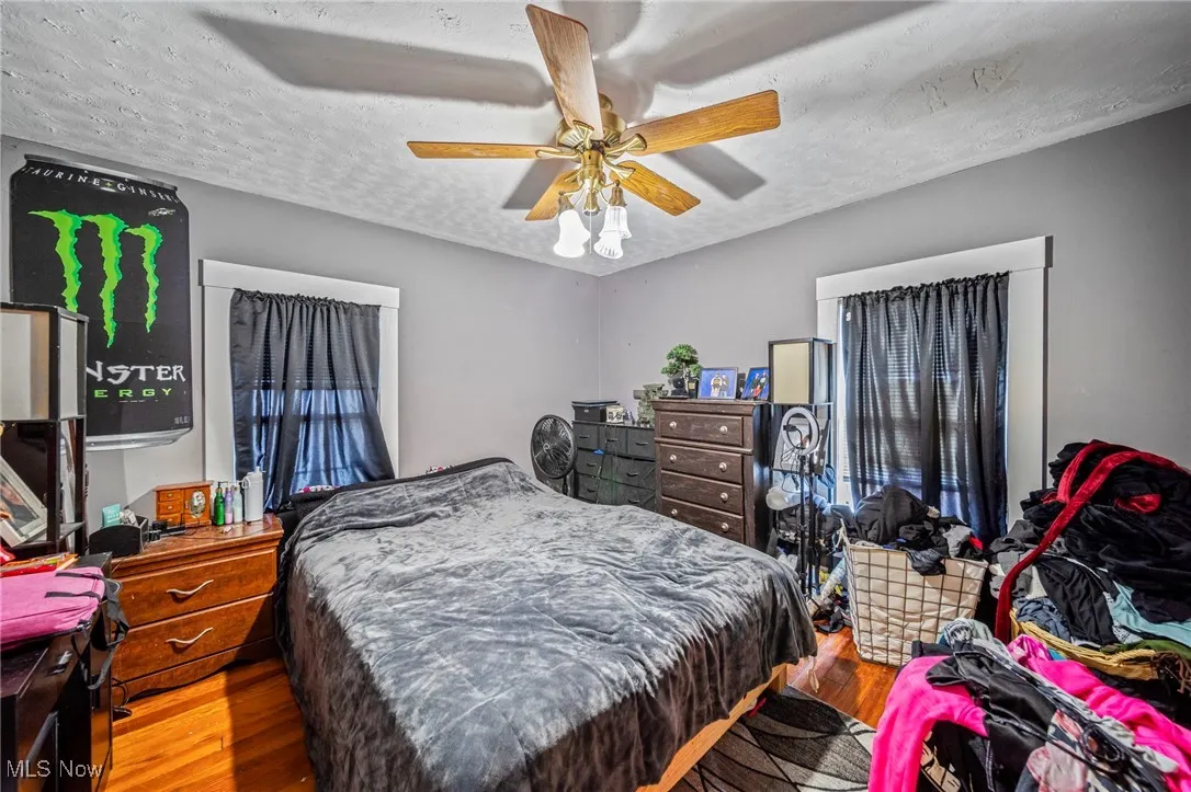 Bedroom with a textured ceiling, a ceiling fan, and wood finished floors