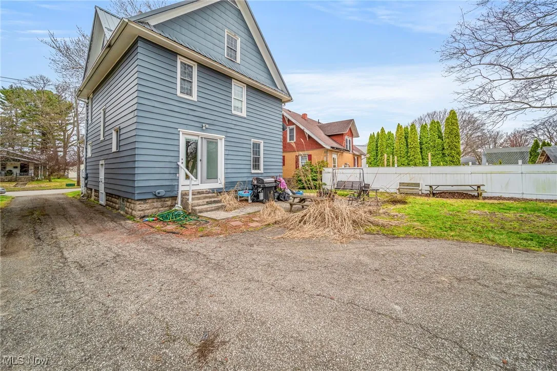 Back of property featuring entry steps, driveway, and fence