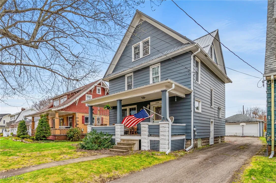 American foursquare style home featuring a detached garage, a front lawn, an outdoor structure, and covered porch
