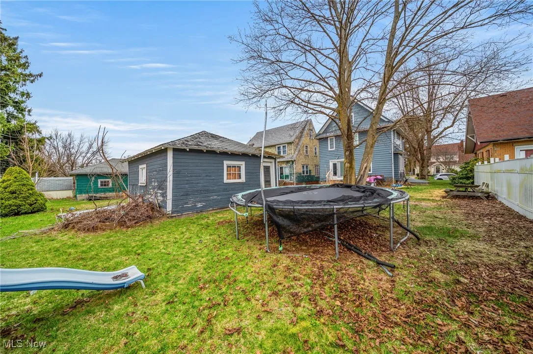 View of yard featuring an outdoor structure, fence, and a trampoline