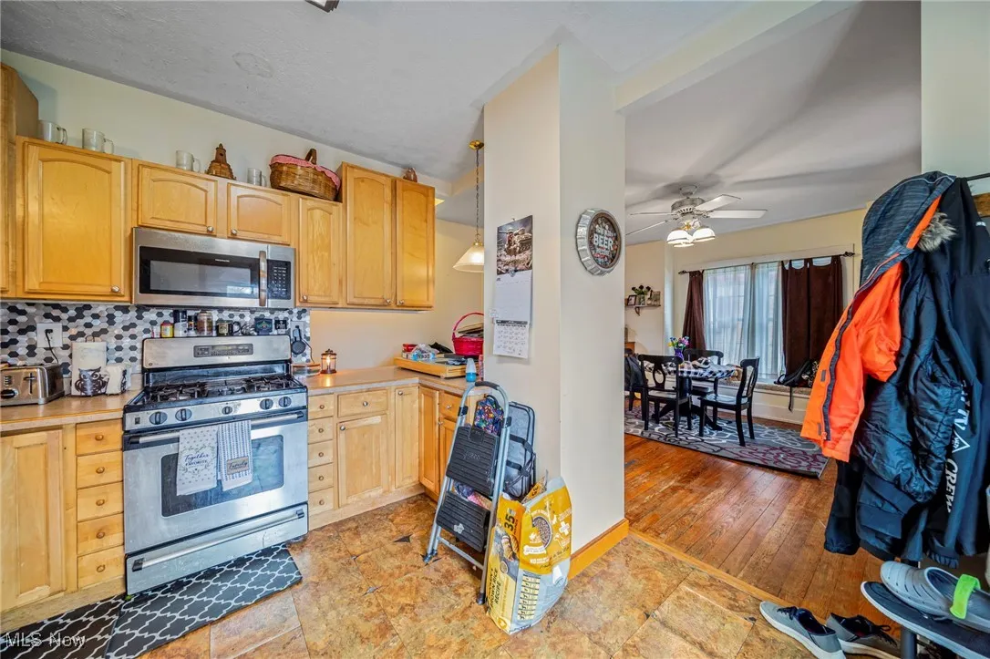 Kitchen featuring backsplash, light countertops, appliances with stainless steel finishes, and ceiling fan