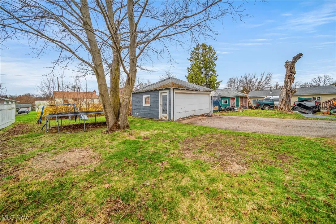 View of yard featuring a trampoline, fence, an outbuilding, and a detached garage