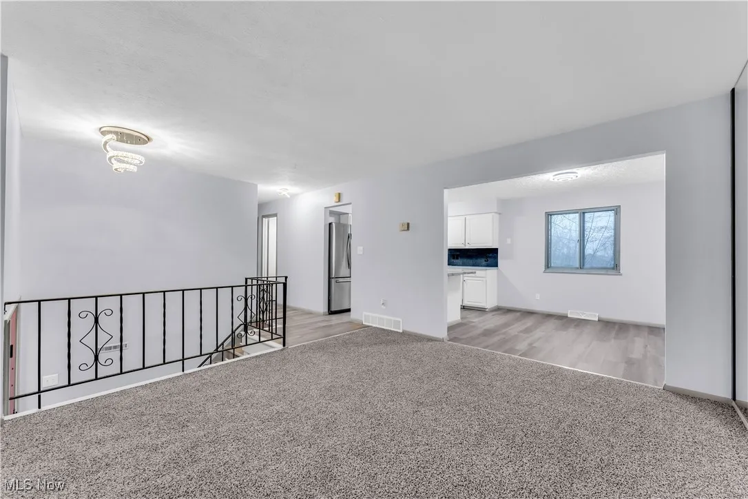 Unfurnished room with light carpet, light wood-style floors, and visible vents