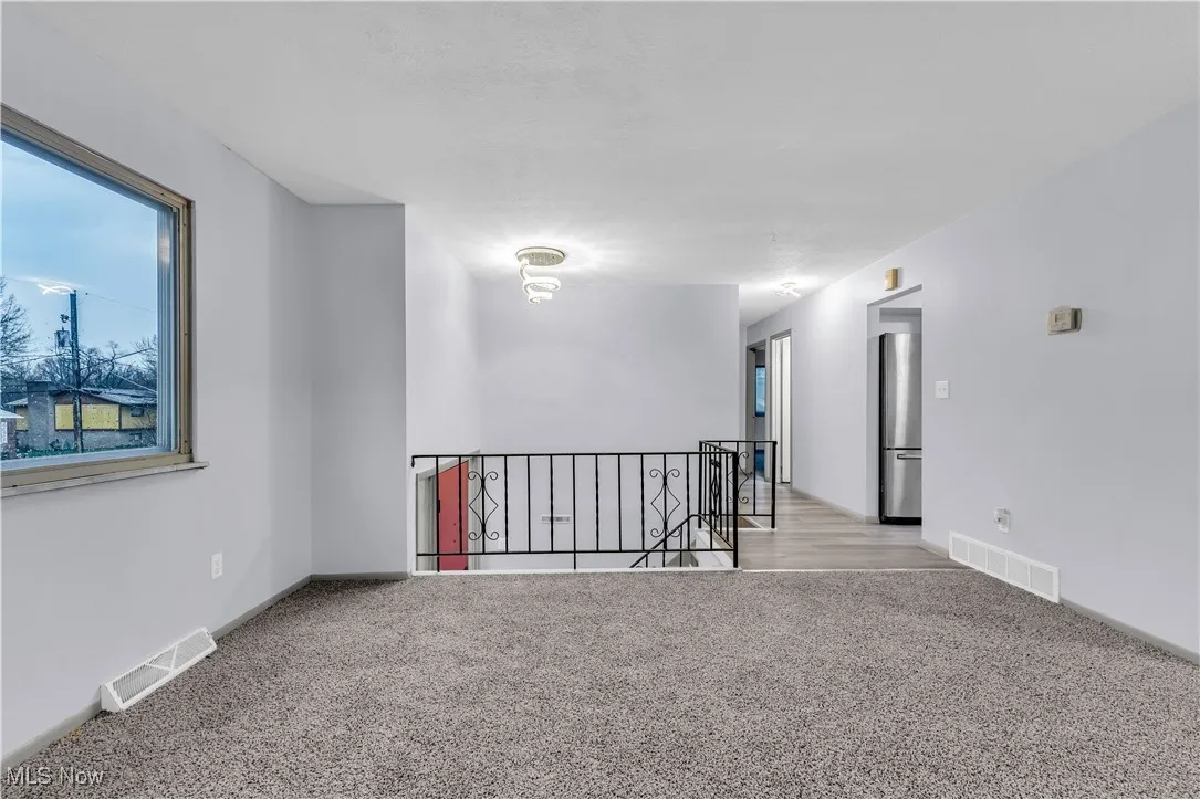 Carpeted spare room featuring baseboards and visible vents