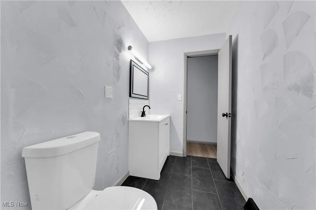 Bathroom featuring tile patterned flooring, vanity, baseboards, and toilet