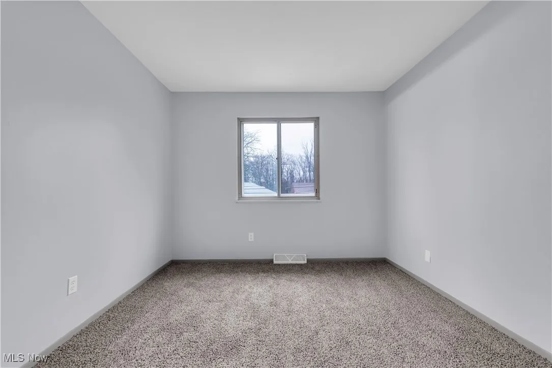 Carpeted empty room with visible vents