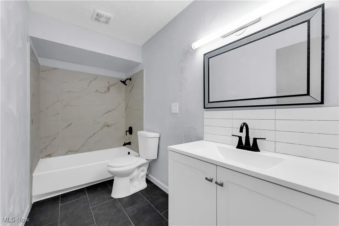 Bathroom featuring bathing tub / shower combination, vanity, visible vents, toilet, and backsplash