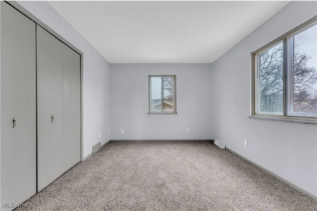 Unfurnished bedroom with a closet, visible vents, and light colored carpet