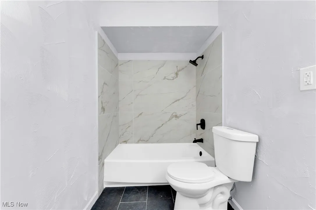 Full bathroom featuring toilet, shower / tub combo, and tile patterned flooring