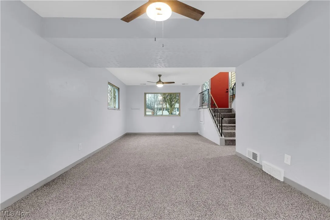 Unfurnished living room featuring visible vents, carpet floors, baseboards, and ceiling fan