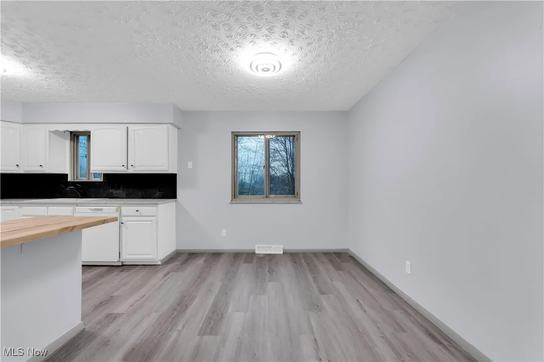 Kitchen featuring visible vents, white cabinets, dishwasher, butcher block counters, and light wood finished floors