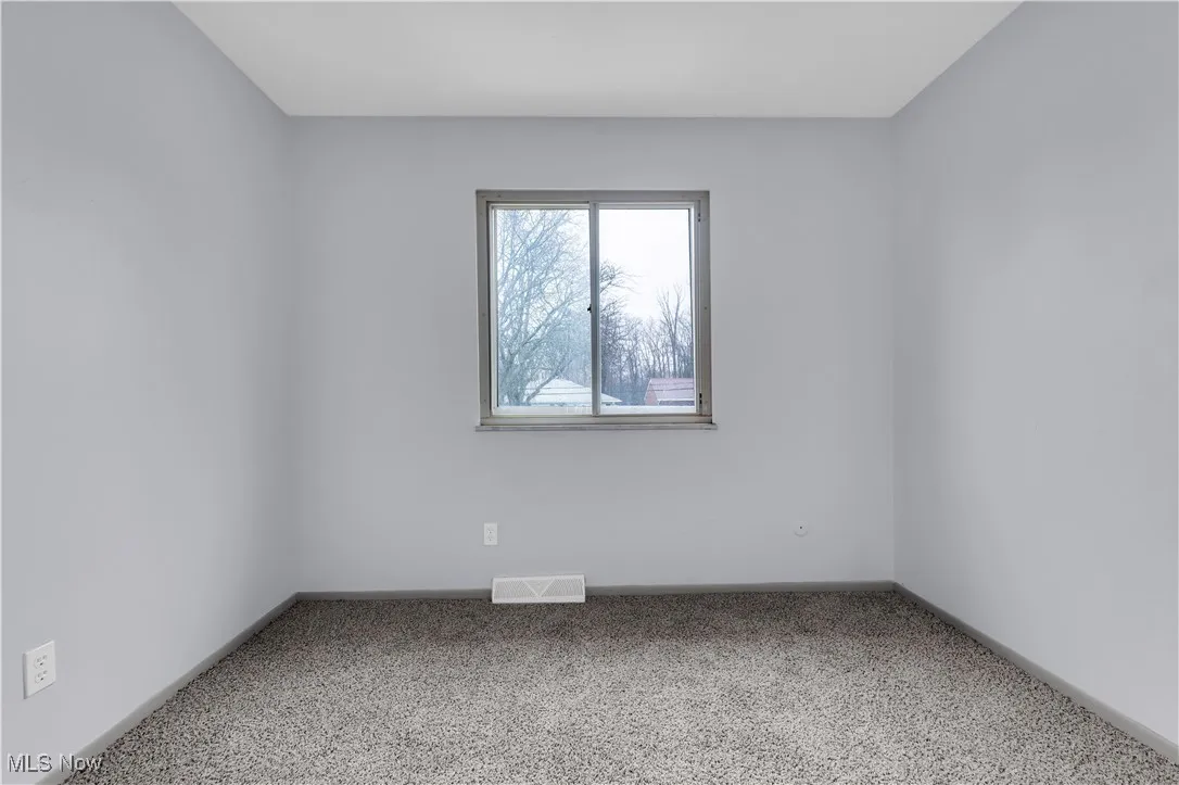 Spare room with carpet flooring, visible vents, and baseboards