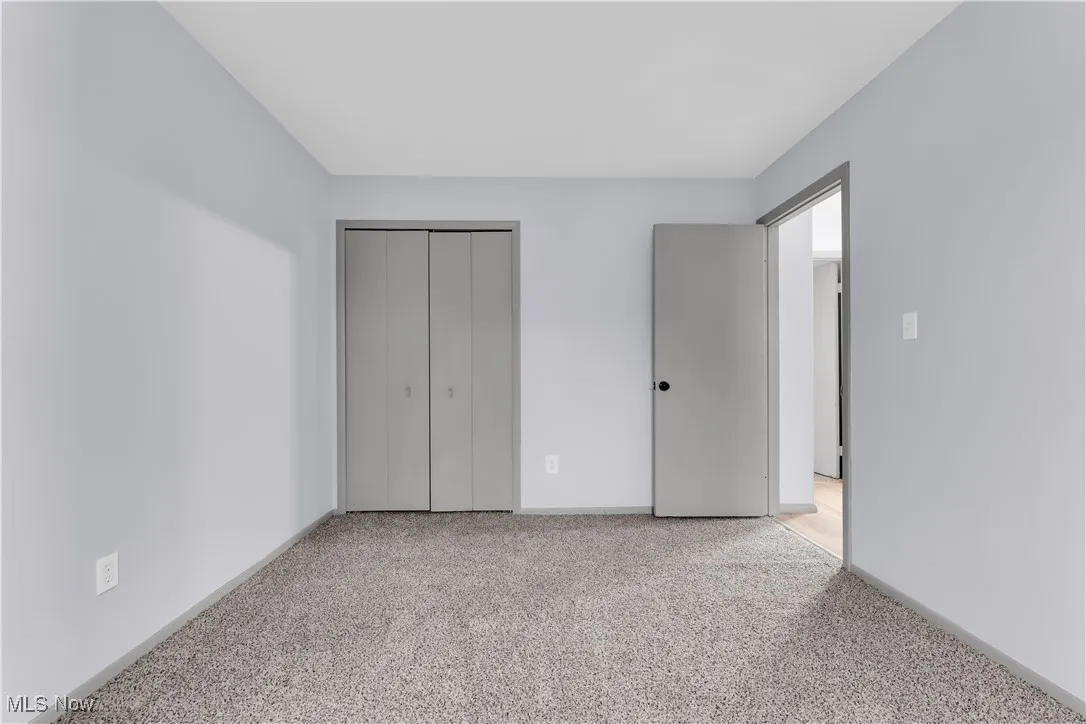 Unfurnished bedroom featuring a closet, baseboards, and carpet