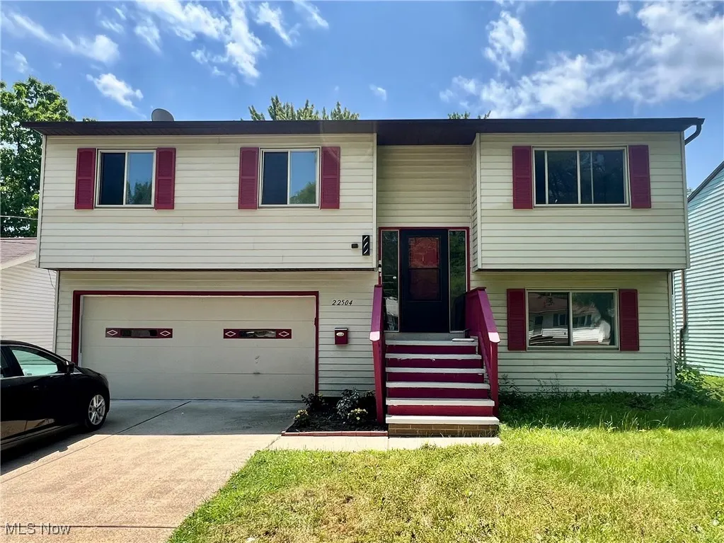 Split foyer home with an attached garage, driveway, and a front lawn