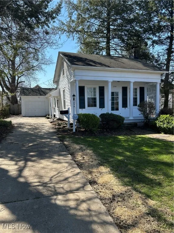View of front facade featuring concrete driveway, an outdoor structure, a front lawn, a garage, and fence