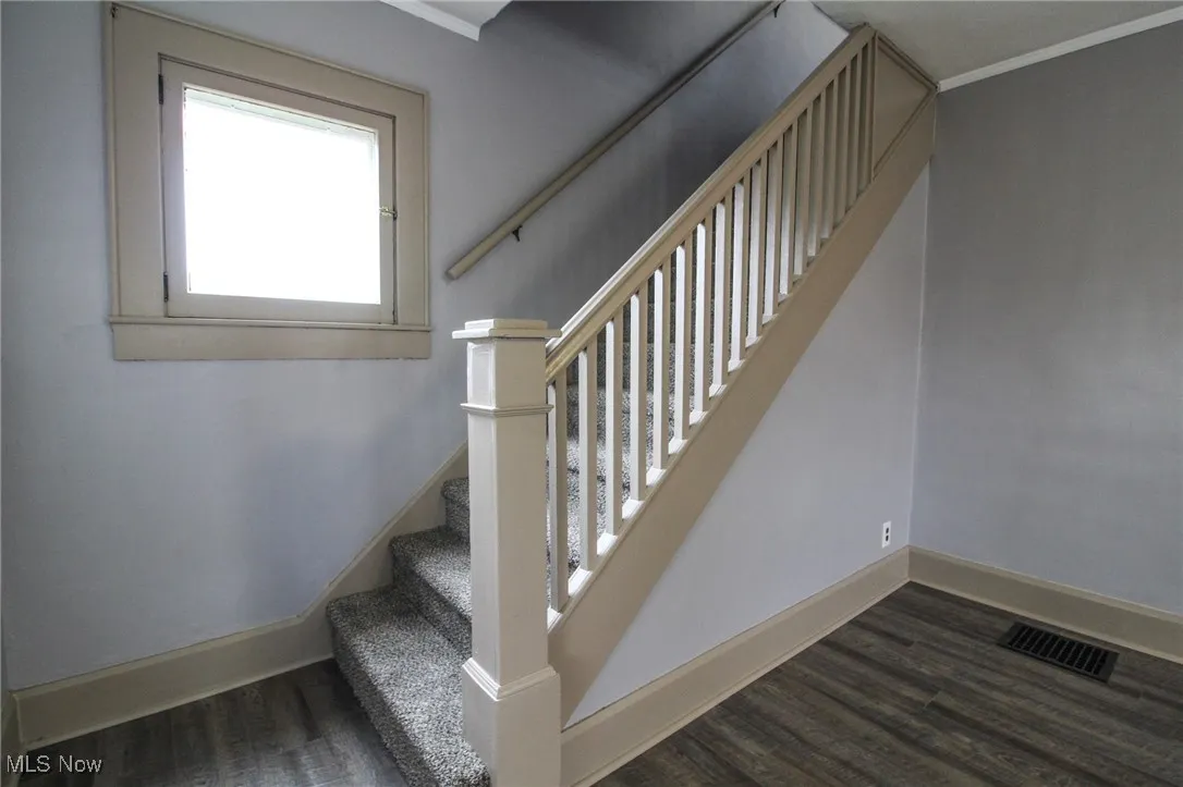 Stairs with visible vents, baseboards, and wood finished floors