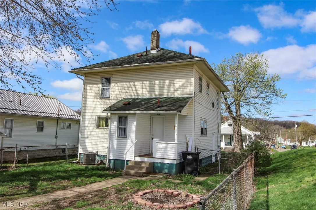 Rear view of house featuring cooling unit, a lawn, a porch, fence, and a chimney