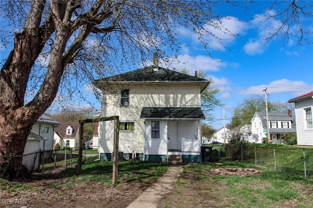 Rear view of property featuring entry steps, a fenced backyard, and a lawn