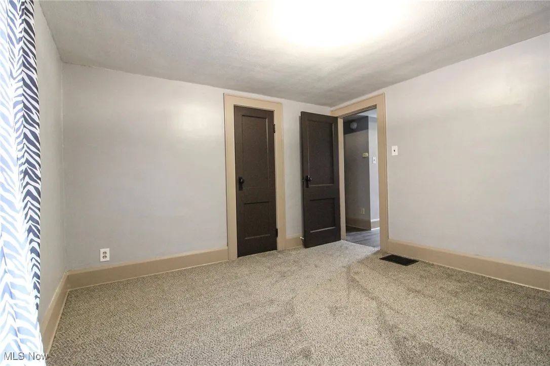 Carpeted empty room featuring a textured ceiling, baseboards, and visible vents