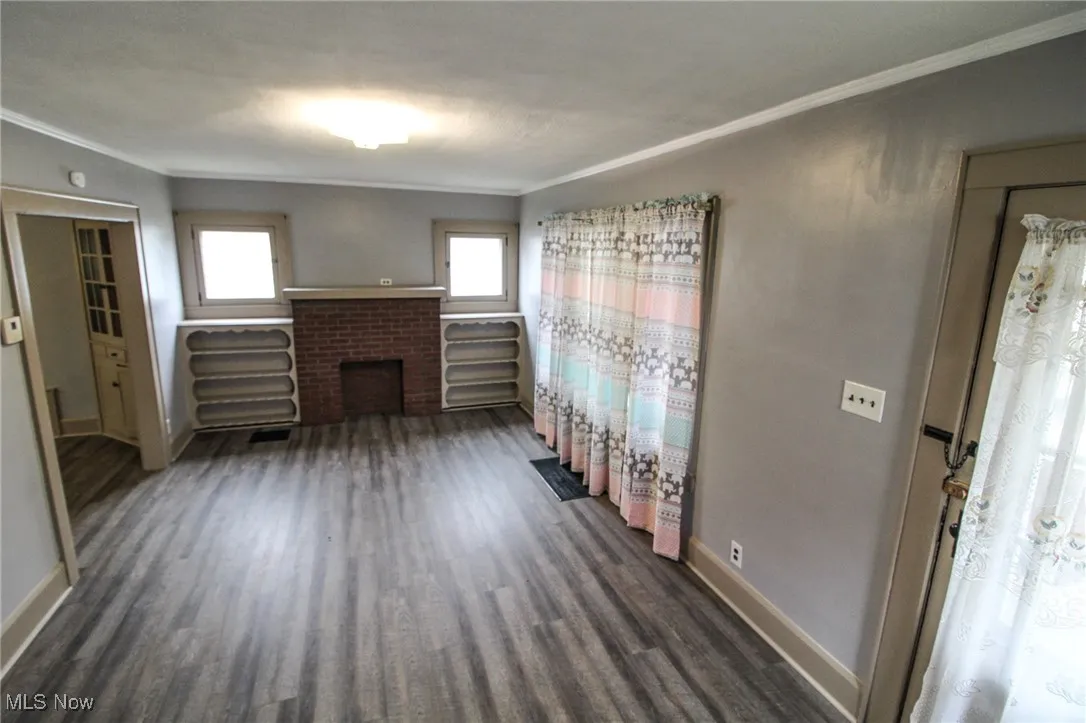 Unfurnished living room with dark wood-type flooring, crown molding, and a wealth of natural light