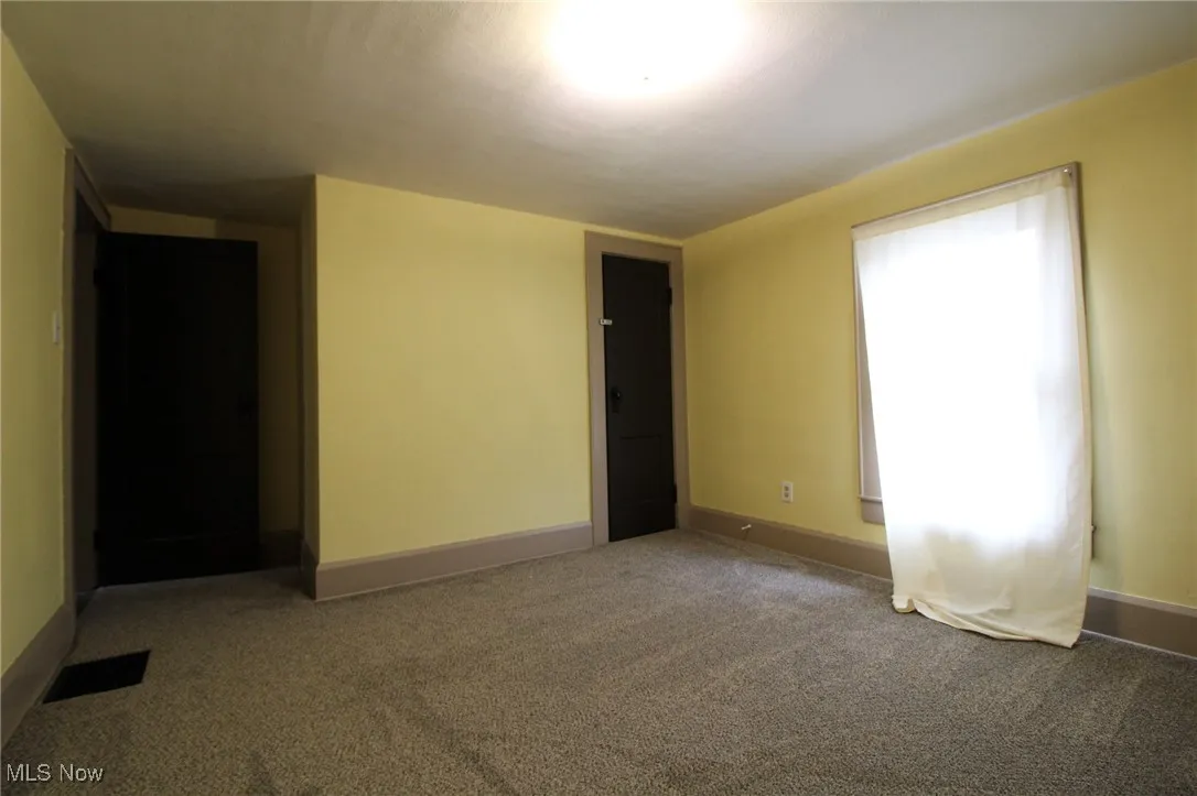 Empty room featuring carpet flooring, baseboards, and visible vents