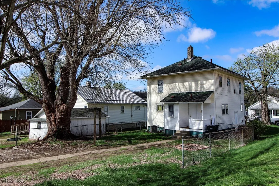 Back of house with a yard, fence, and a chimney