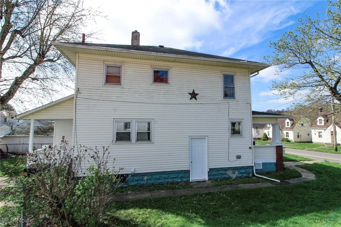 Rear view of property with a chimney and a lawn