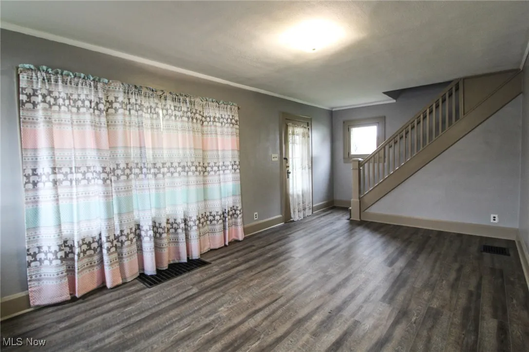Entrance foyer with crown molding, visible vents, stairway, wood finished floors, and baseboards