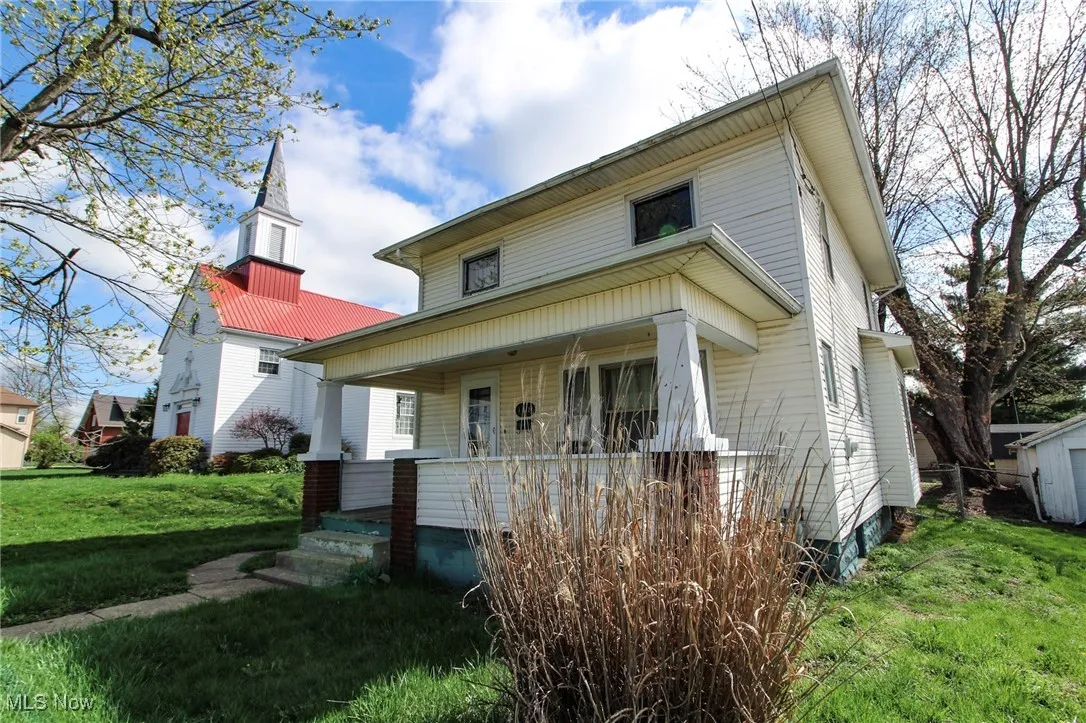 Traditional style home featuring covered porch and a front yard