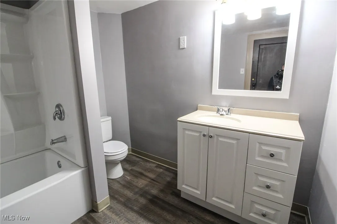 Full bath featuring vanity, baseboards, shower / washtub combination, toilet, and wood finished floors