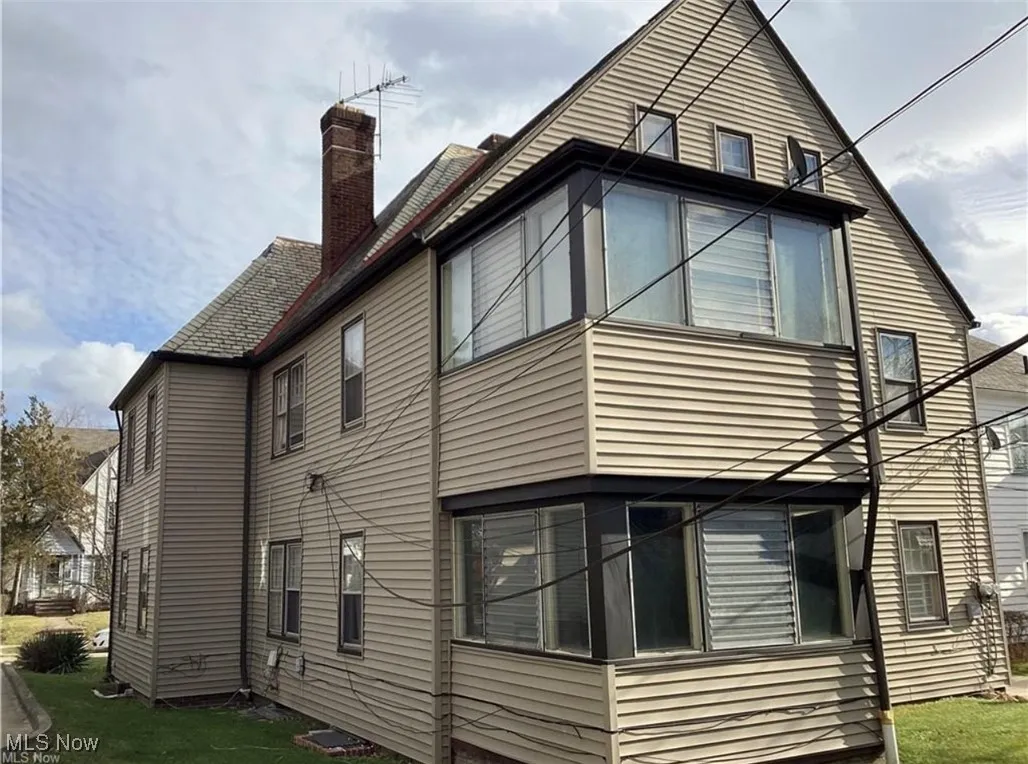 View of property exterior with a chimney and a lawn