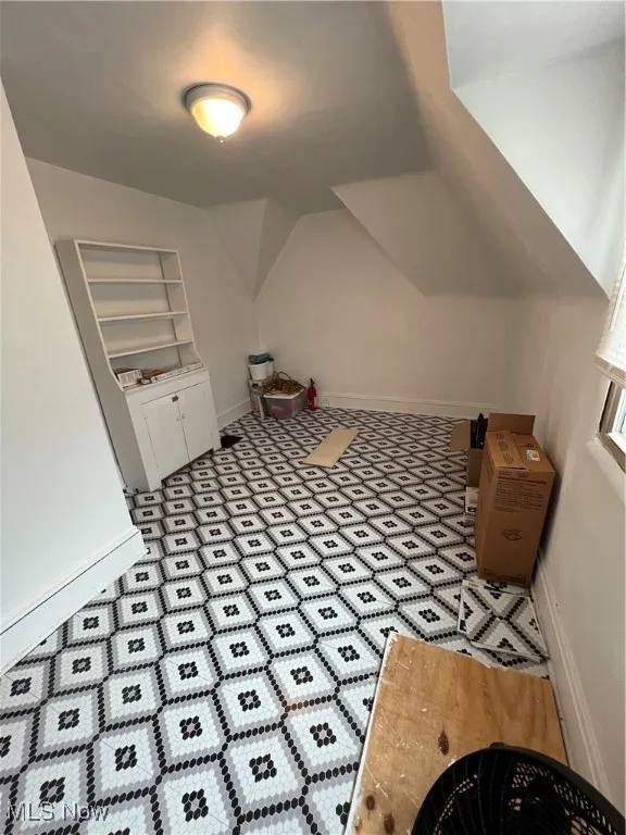 Additional living space featuring baseboards and vaulted ceiling