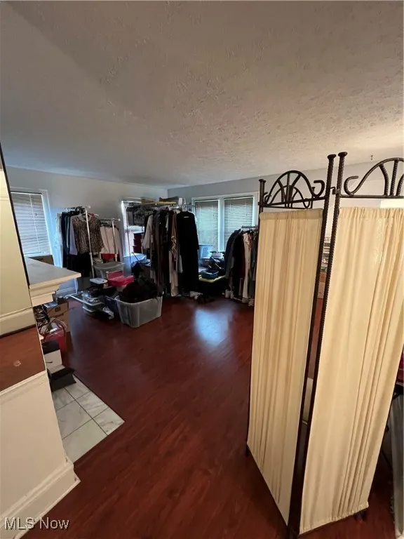 Hall with a textured ceiling and wood finished floors