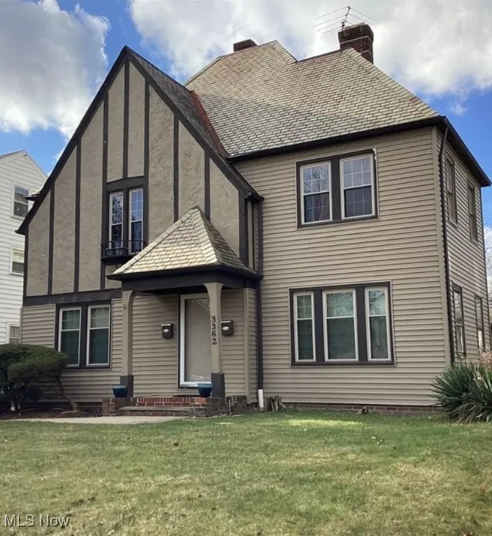 Tudor house featuring a front yard and a chimney