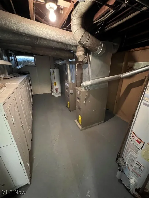 Basement featuring water heater, washer / clothes dryer, and heating unit