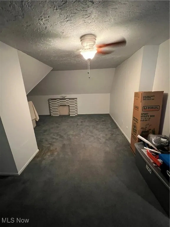 Bonus room featuring a textured ceiling, carpet flooring, a ceiling fan, and vaulted ceiling