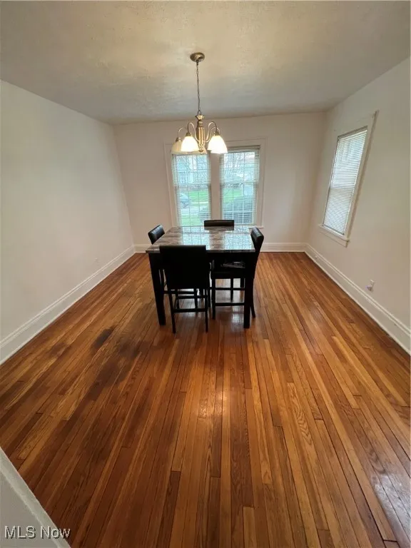 Dining area with a notable chandelier, dark wood finished floors, and​​‌​​​​‌​​‌‌​‌‌​​​‌‌​‌​‌​‌​​​‌​​ baseboards