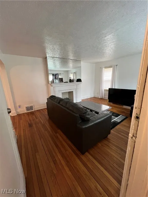 Living room featuring visible vents, hardwood / wood-style flooring, and a textured ceiling