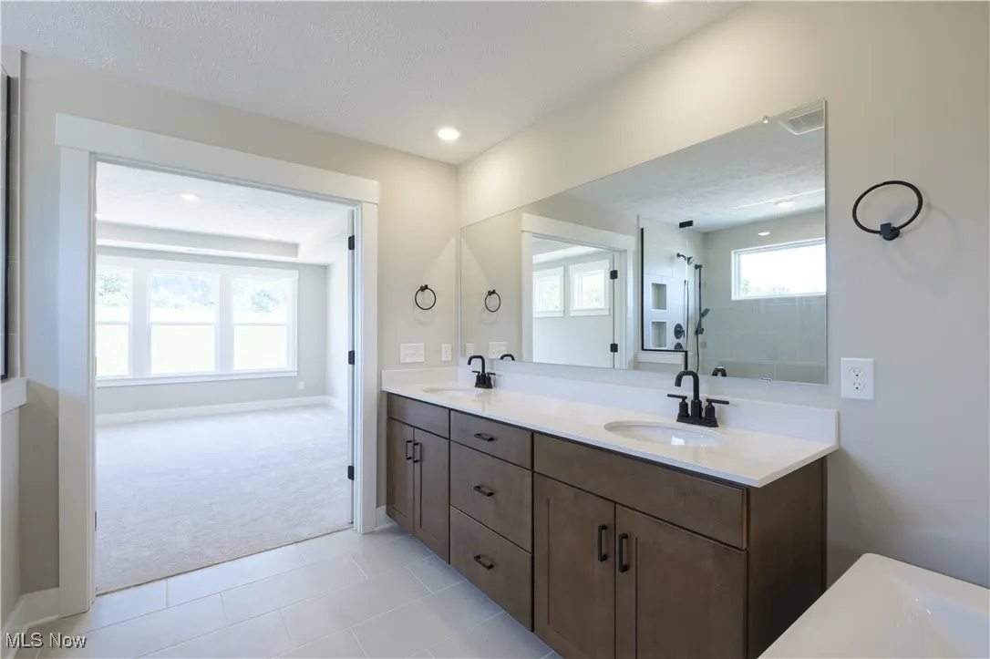 Full bathroom with double vanity, a textured ceiling, a shower, tile patterned flooring, and recessed lighting