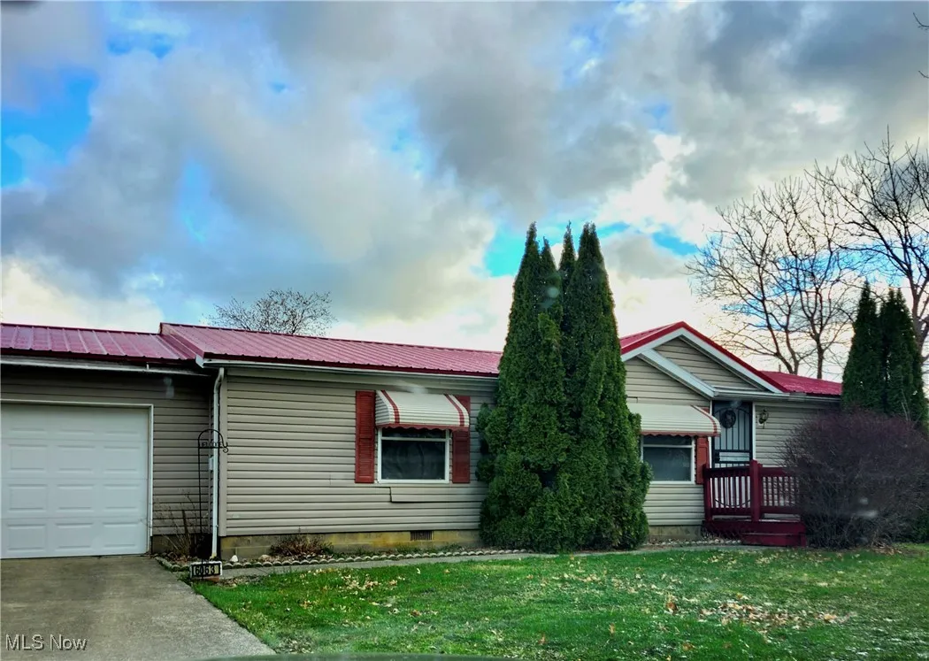 Single story home with concrete driveway, crawl space, an attached garage, a front lawn, and metal roof