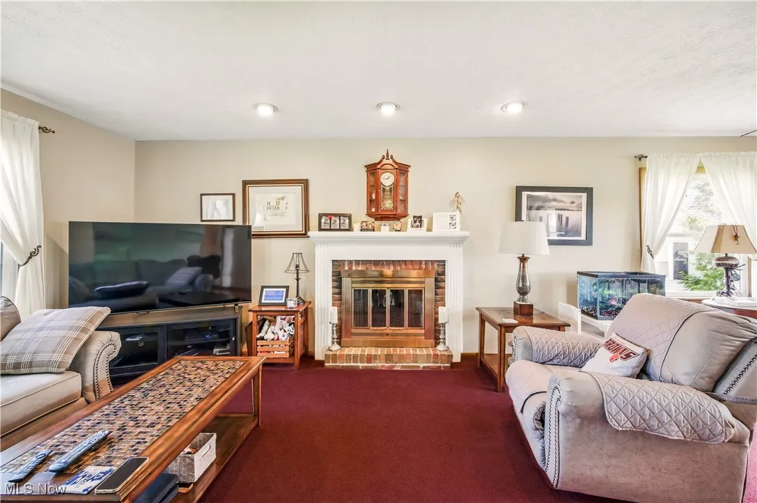 Living room with dark colored carpet and a brick fireplace